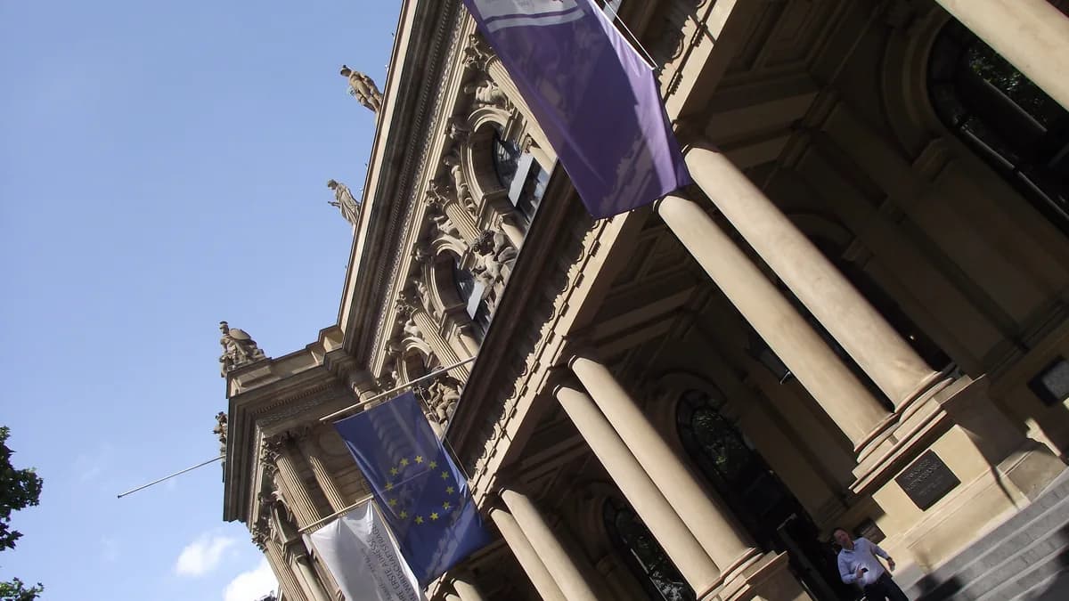 Frankfurt borsasının kumtaşı cephesi, önünde AB bayrağı ve borsa kurumunun bayrakları (temsilî görsel)