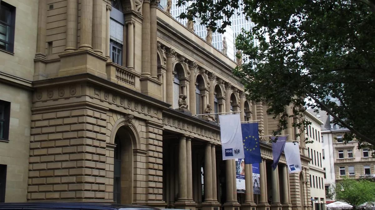 Frankfurt borsasının cephesi, AB bayrağı ve kurum bayraklarıyla, önünde park hâlinde birkaç araba (temsilî görsel)