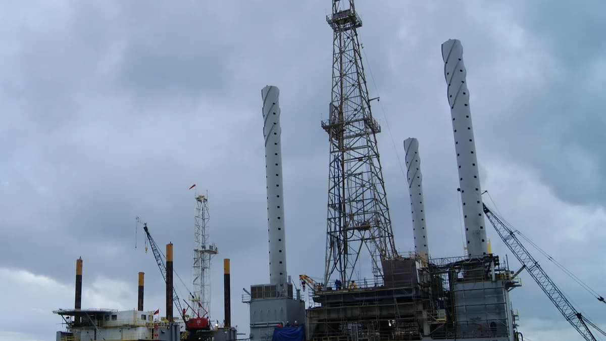 Trinidad açıklarında bir liman rıhtımına yanaşmış açık deniz petrol platformu, sondaj kulesi ve destek bacaklarıyla (temsilî görsel)